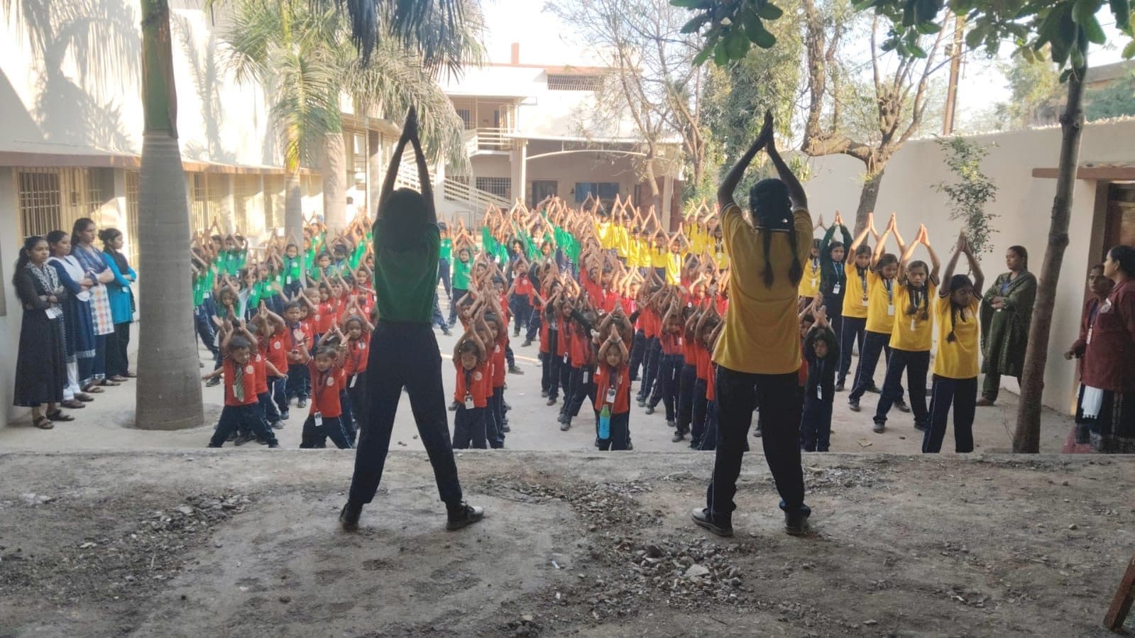 Students lined up across the school courtyard for morning drill, led by two teachers
