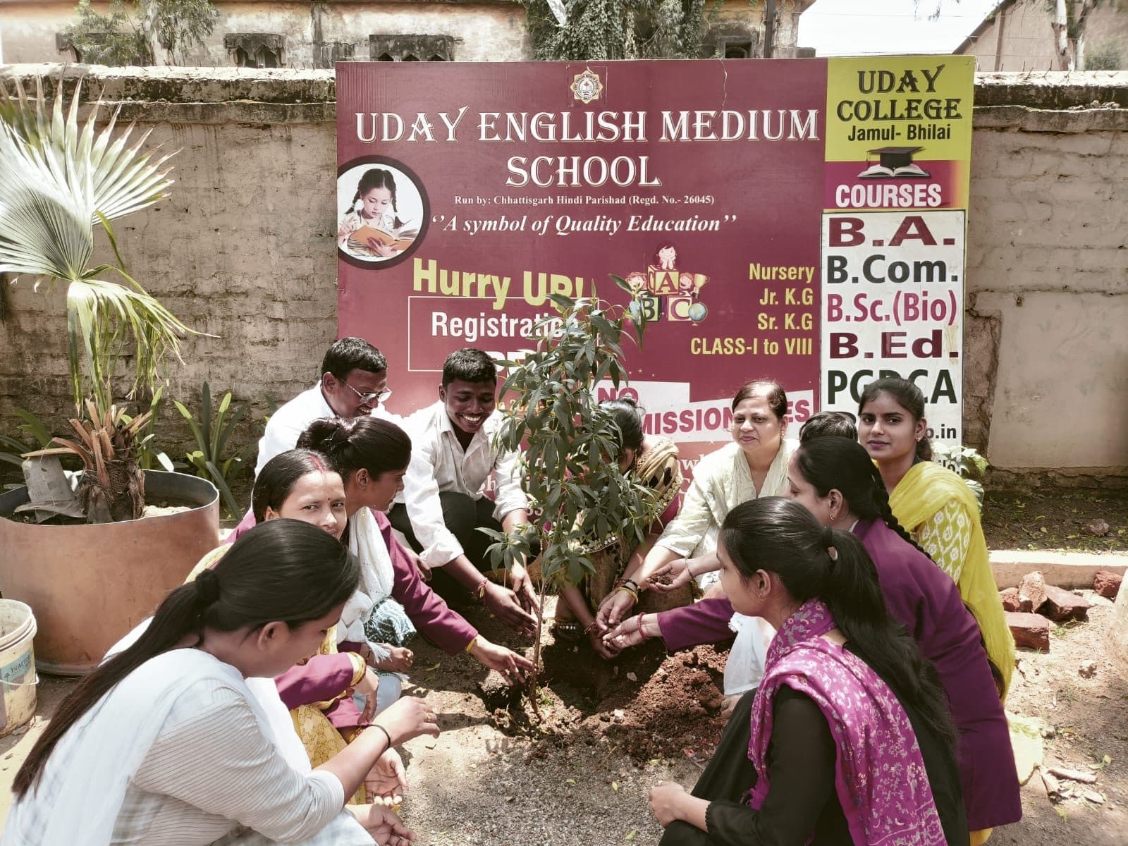 Teachers and students planting a sapling together on the school grounds